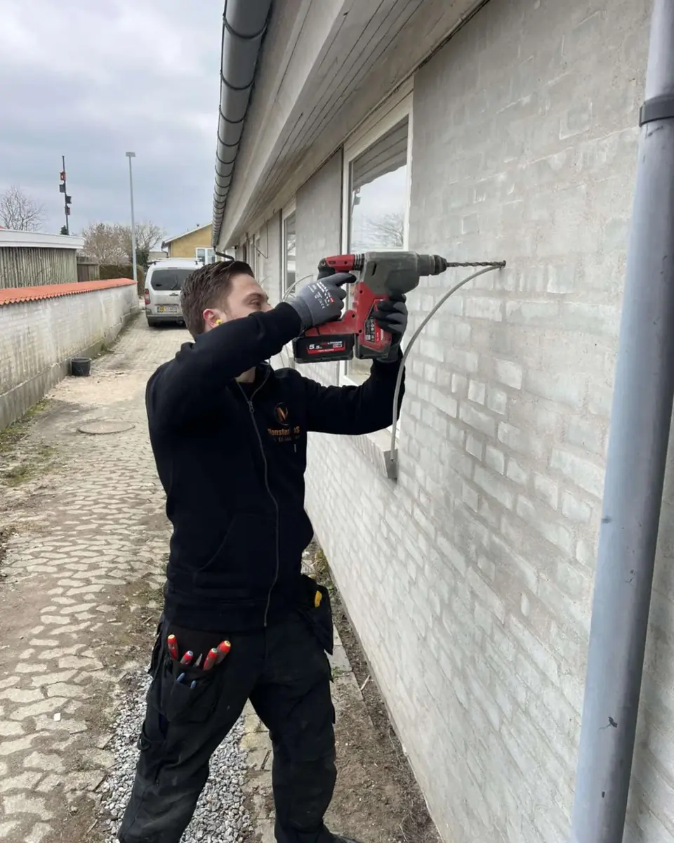 Elektriker fra Mønster EL borer i en murstensvæg med en kraftig borehammer